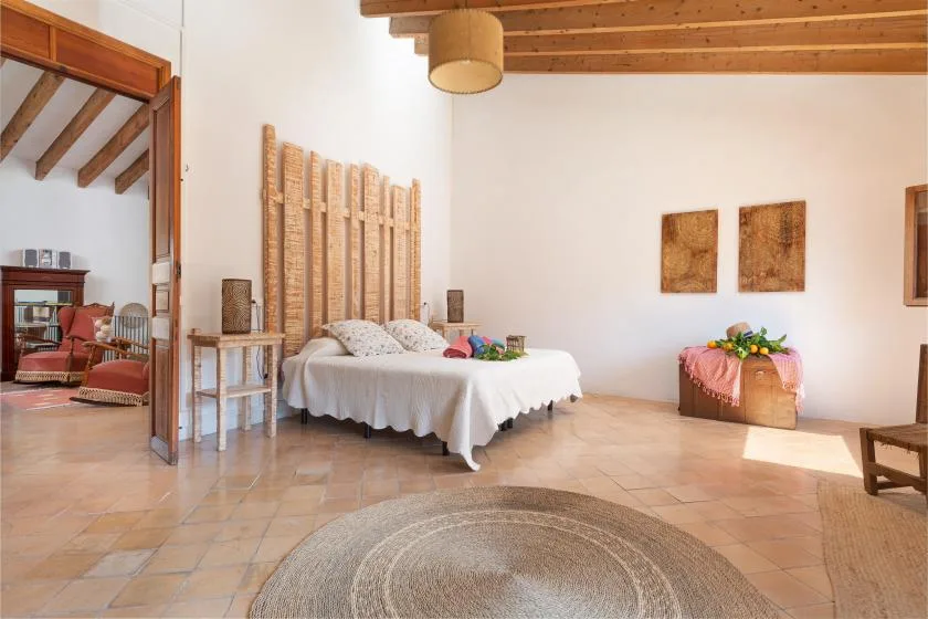 A bedroom with a white bed, woven headboard, and tiled floor.