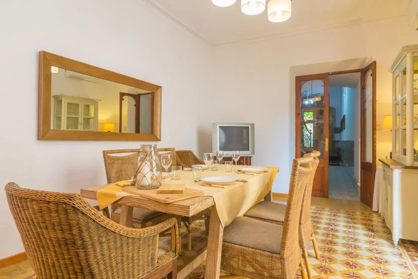 A dining area with a wooden table set with dishes and surrounded by seating.