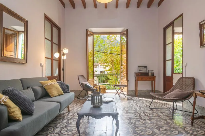 A bright living room with seating around a low table and an open balcony doorway.