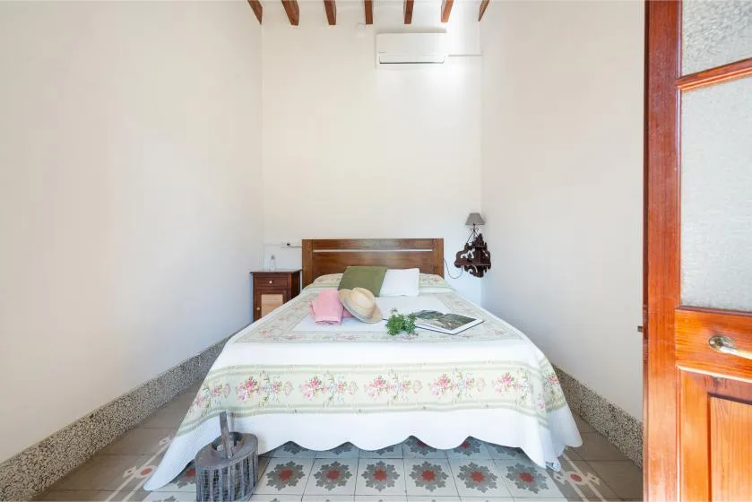 A bedroom with a bed beneath exposed wooden ceiling beams.