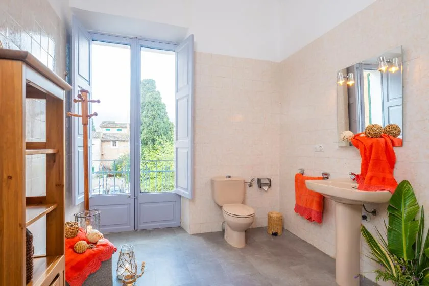 A bright bathroom with a sink, toilet, and an open window.