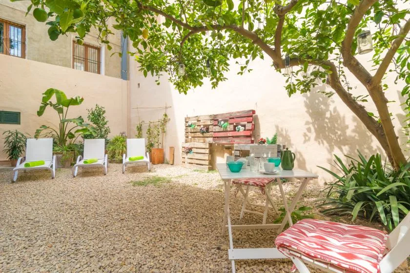 Un patio frondoso con asientos al aire libre y una mesa pequeña.