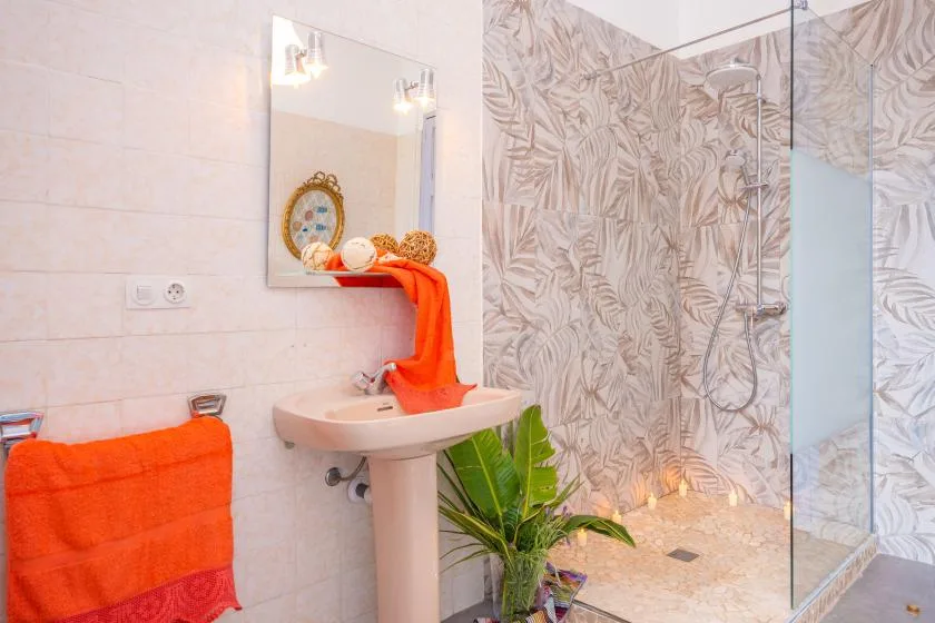 A bathroom with a pedestal sink, mirror, and glass shower.