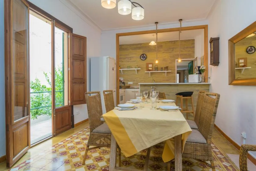 A dining area with a table set beneath pendant lights and large windows.