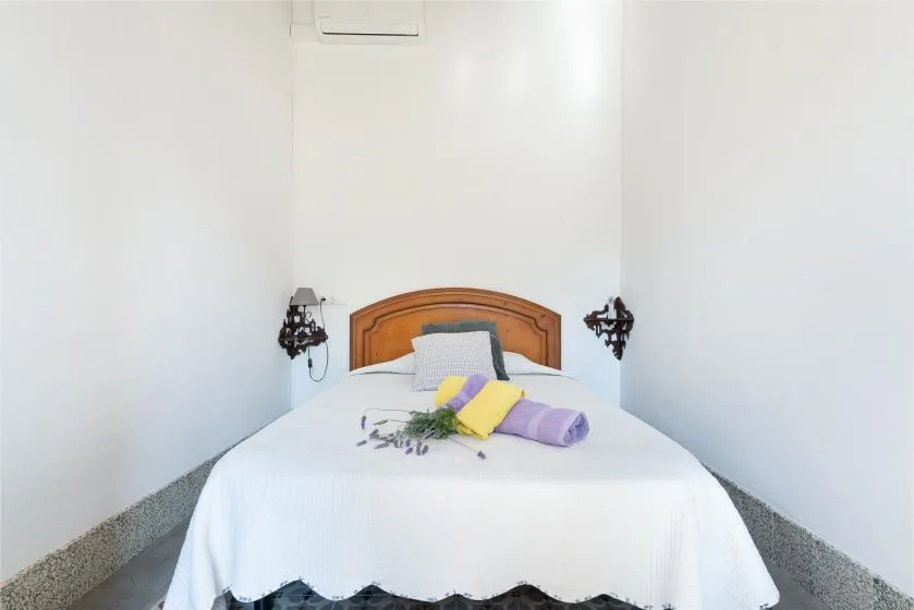 A bedroom with a neatly made bed and colorful towels arranged on top.