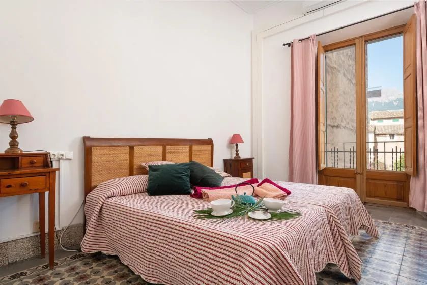 A bedroom with a double bed, bedside tables, and a window with pink curtains.