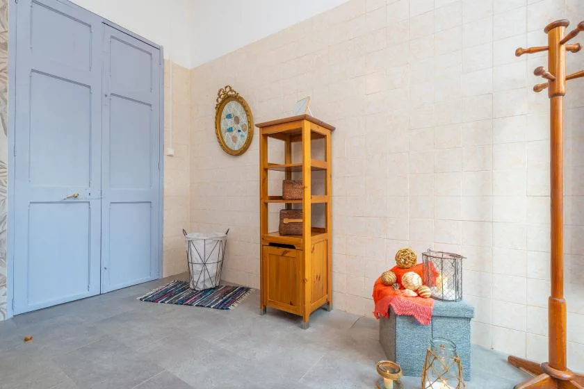 A tiled room with a wooden cabinet, blue doors, and a coat rack.