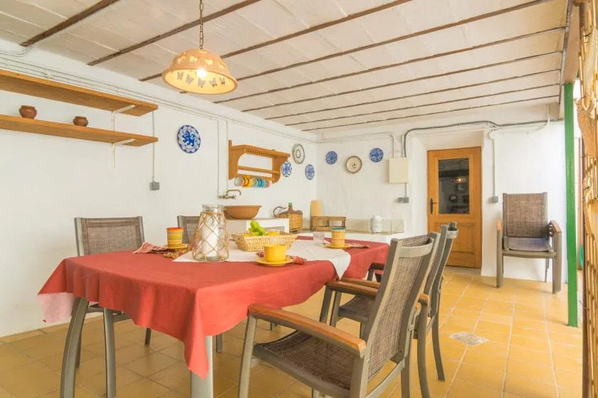 A dining room with a long table set beneath a hanging light.