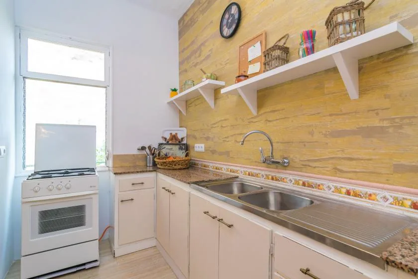 A bright kitchen with a long counter, sink, and white cabinetry.