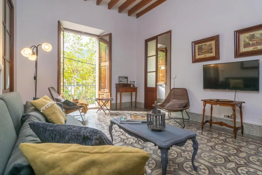 A living room with seating, a coffee table, and tall open windows.