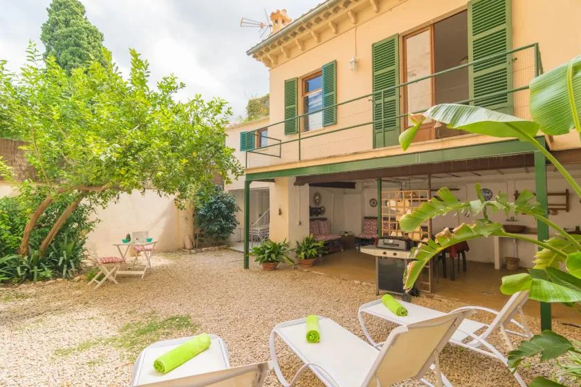 Un patio soleado con asientos al aire libre bajo una terraza sombreada.