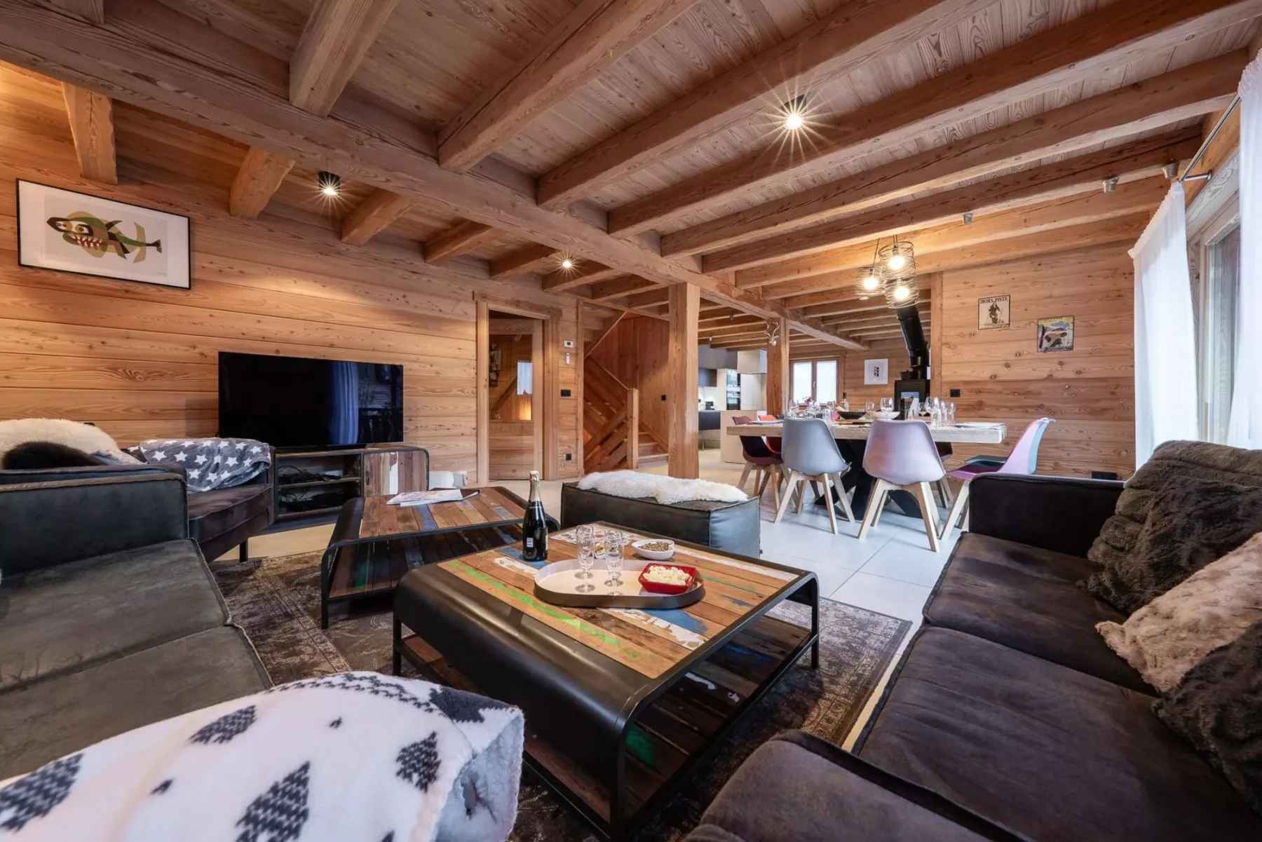 Una sala y comedor con paredes de madera, asientos, una mesa de centro y una mesa de comedor.