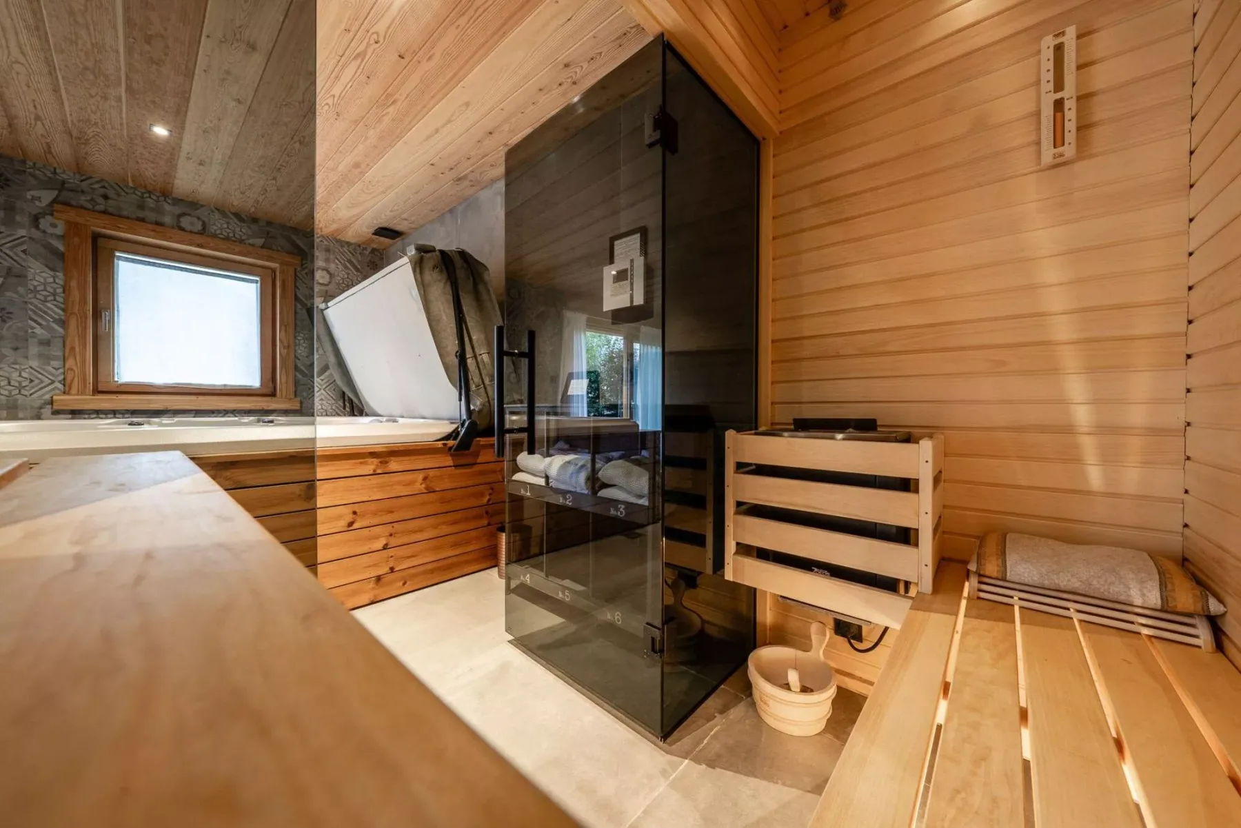 A wood-paneled sauna room with a glass-fronted heater and wooden seating.
