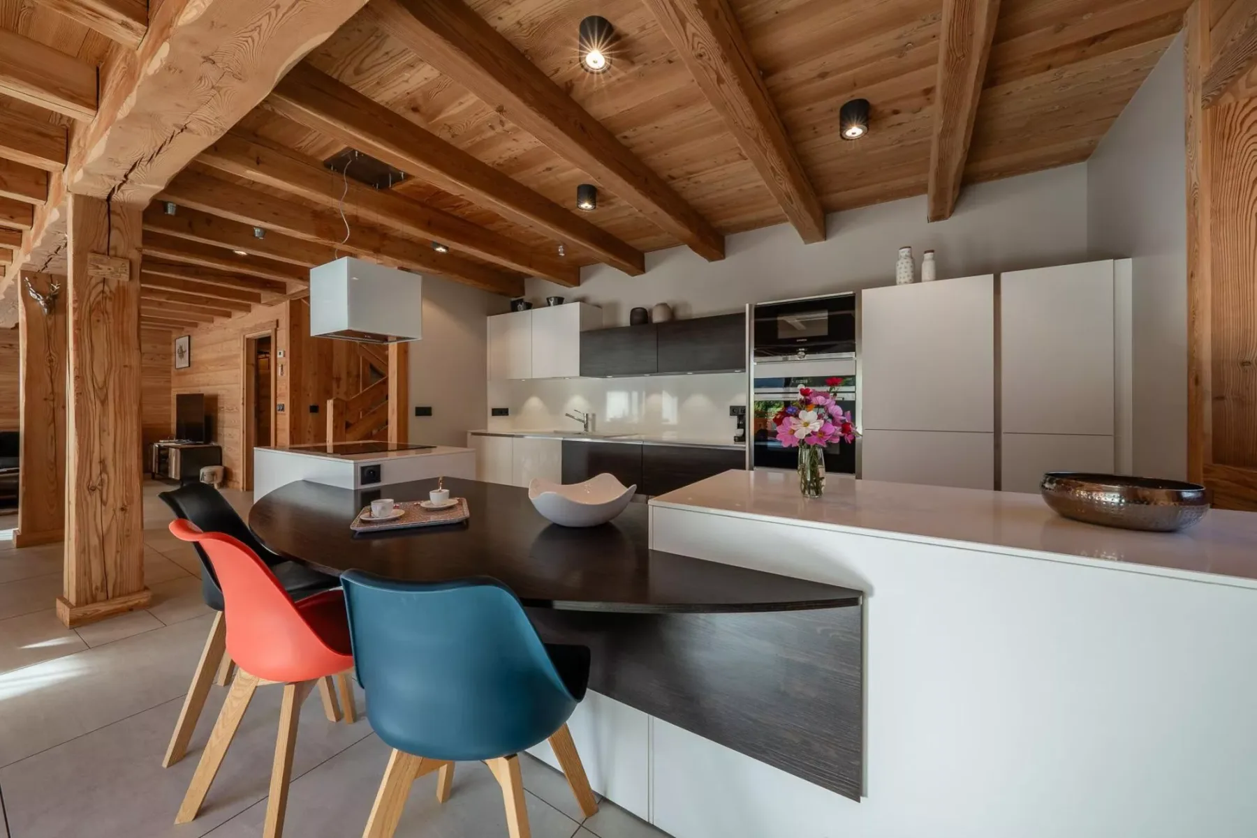 Una cocina moderna con una isla oscura y flores de colores sobre la encimera.