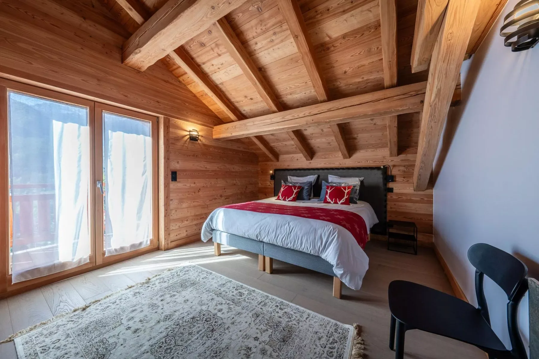 A wood-paneled bedroom with a bed beneath exposed ceiling beams.