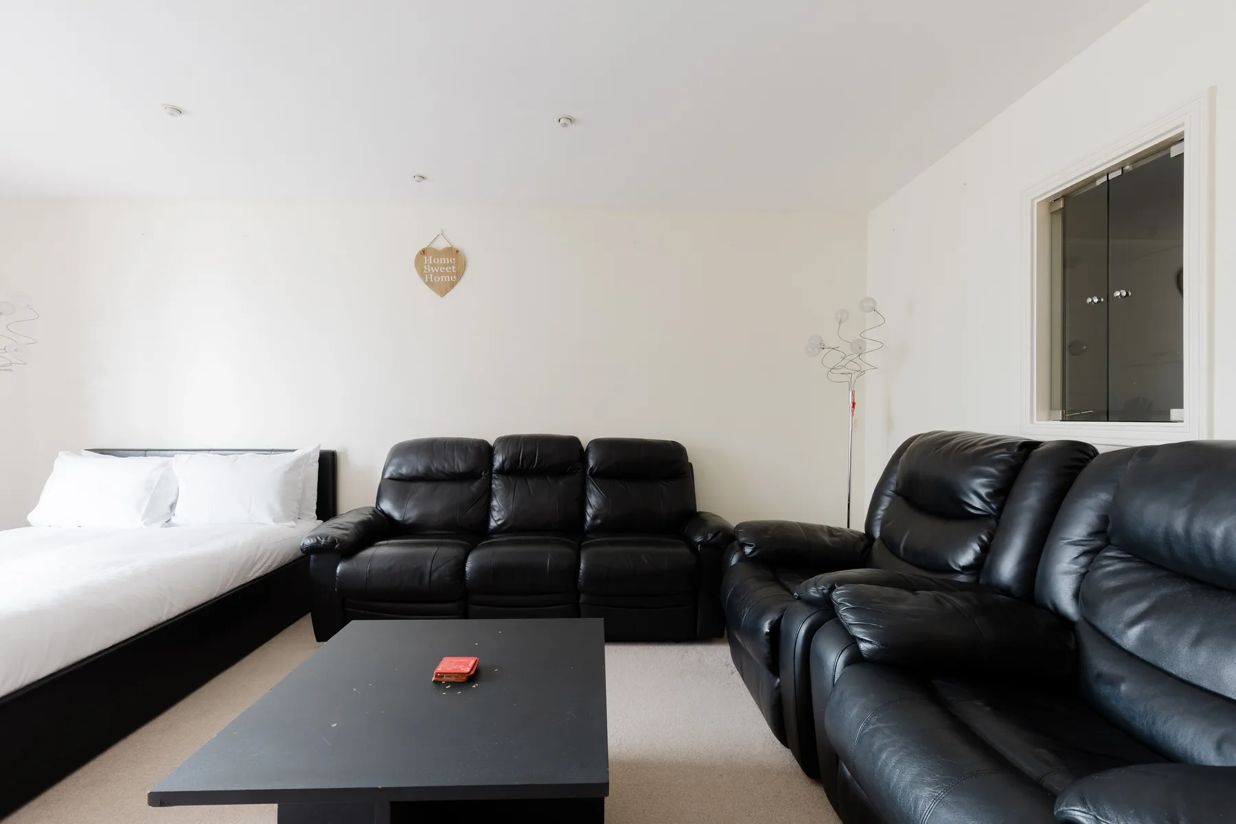 A bedroom with a bed, black seating, and a low table.