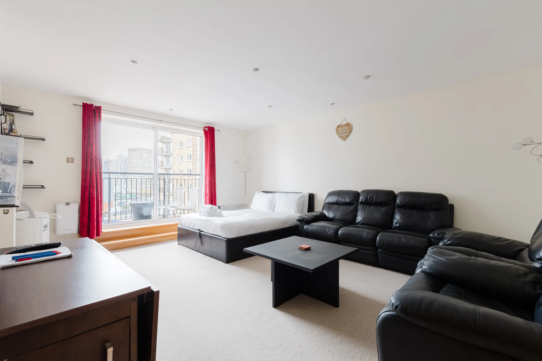 A bright living room with black seating and a large window.