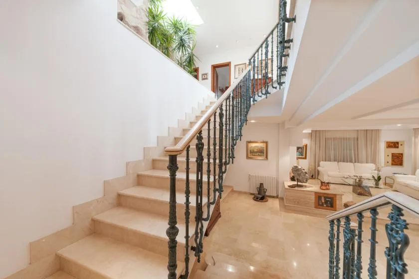 A bright interior staircase with dark railings opens onto a furnished living area.