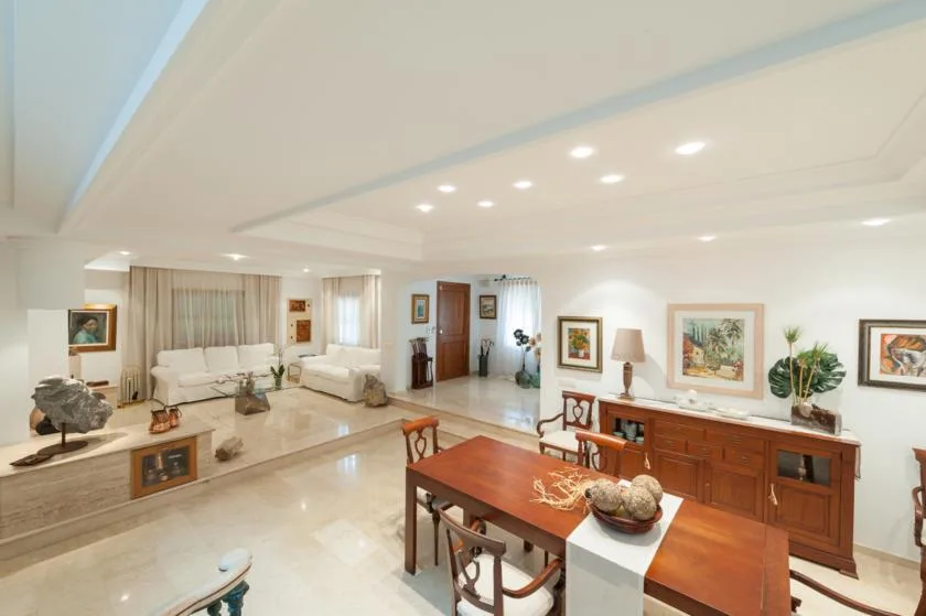 A bright living and dining area with seating, a dining table, and framed artwork.