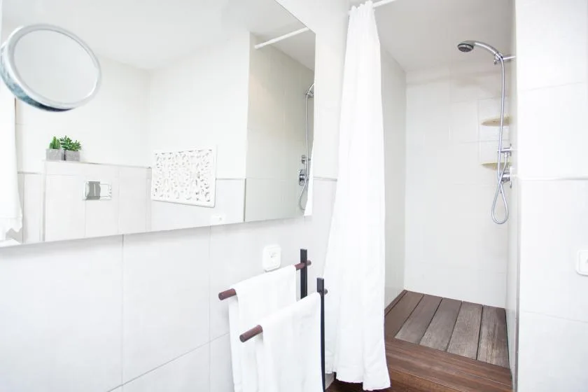 A bright bathroom with a shower and a white curtain.