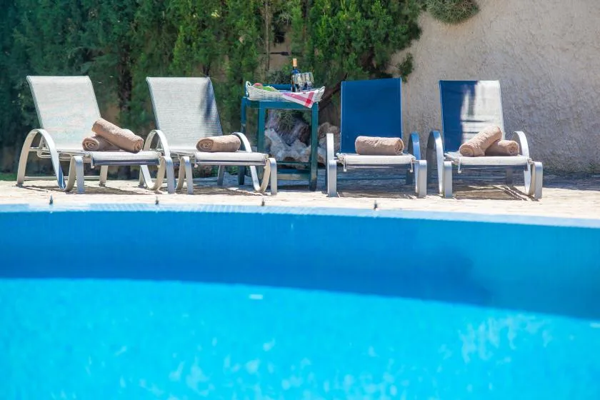 A swimming pool with lounge chairs arranged along the edge.