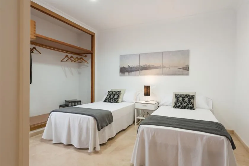 A bedroom with two beds, a shared nightstand, and an open clothes rail.