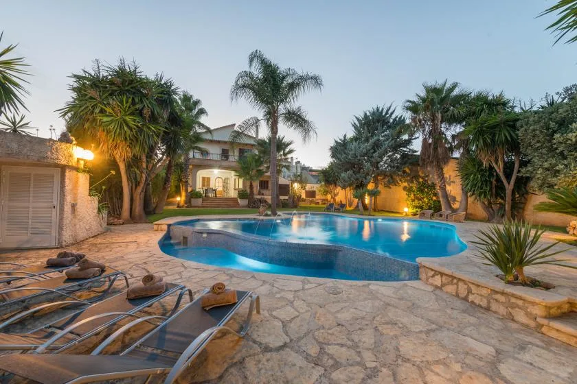 A landscaped outdoor pool area with lounge seating and palm trees.