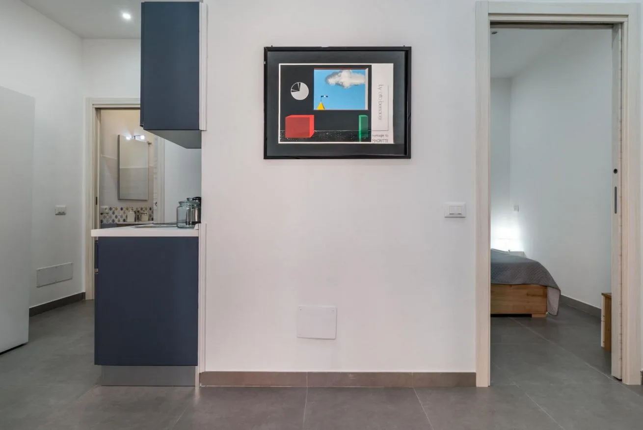 A bright interior hallway opens onto a compact kitchen and a bedroom.