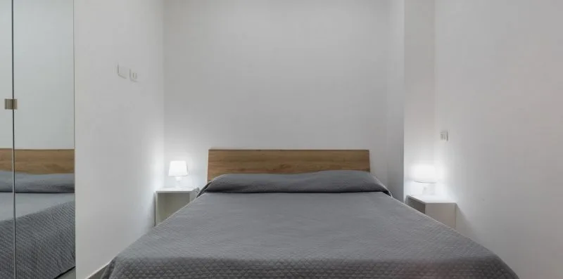 A bedroom with a bed, gray bedding, and small bedside tables.