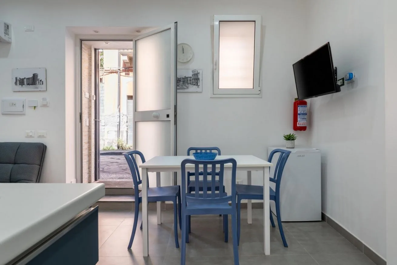 A dining area with blue seating, a table, and a wall-mounted television.