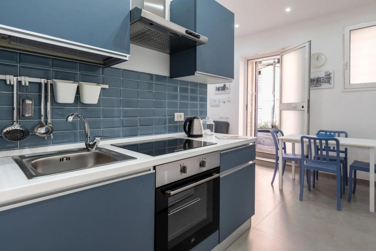 A modern kitchen with blue cabinets, a sink, and a dining table.