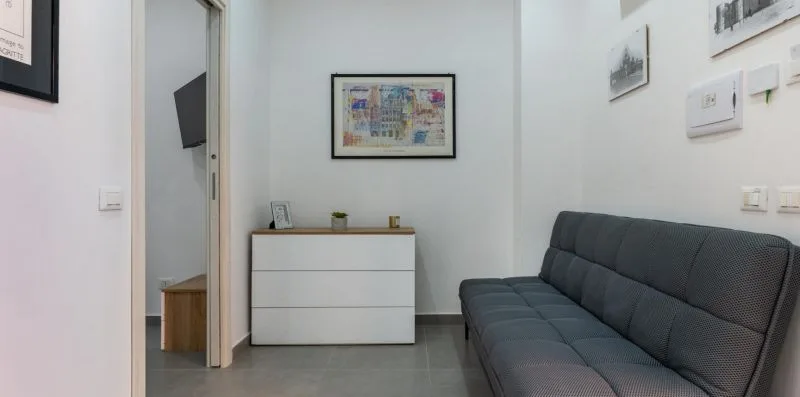 A living room with a dark upholstered sofa and a white cabinet.