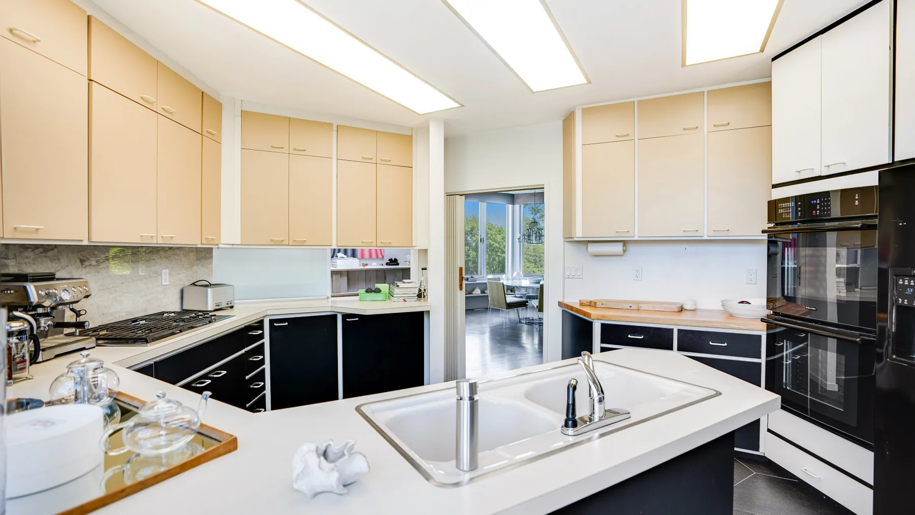 A modern kitchen with pale cabinetry and a central island with a sink.