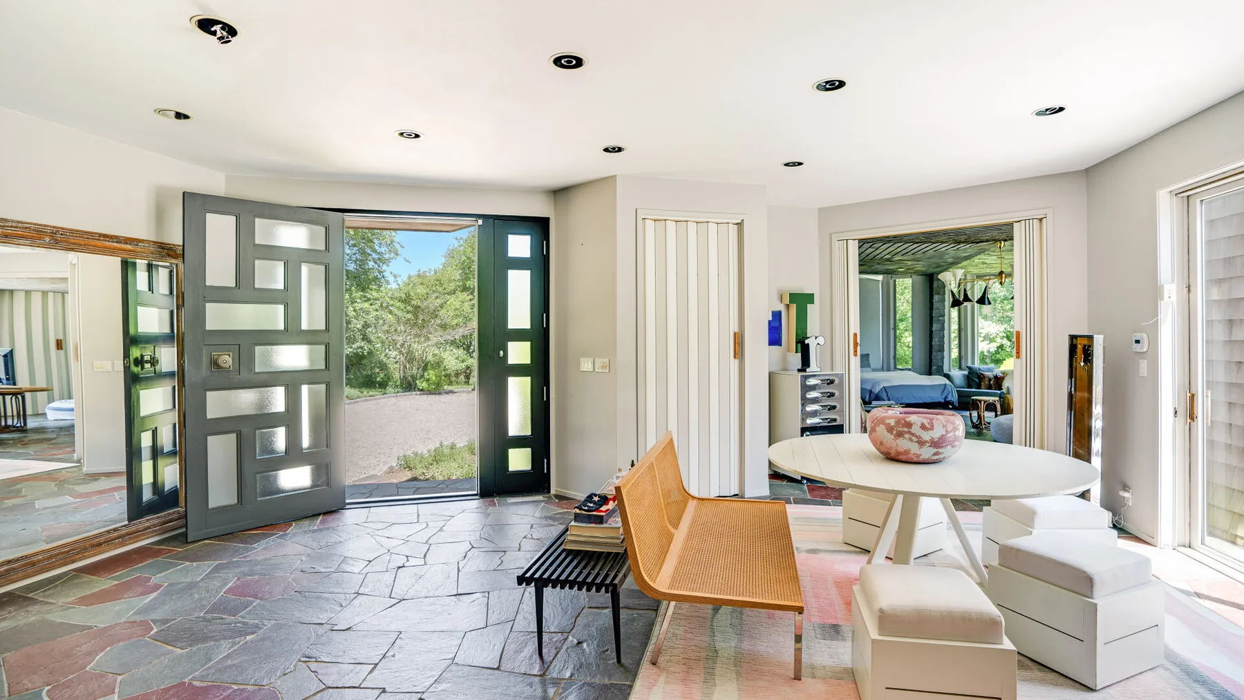 A bright living area opens onto a patio, with a round table and seating.