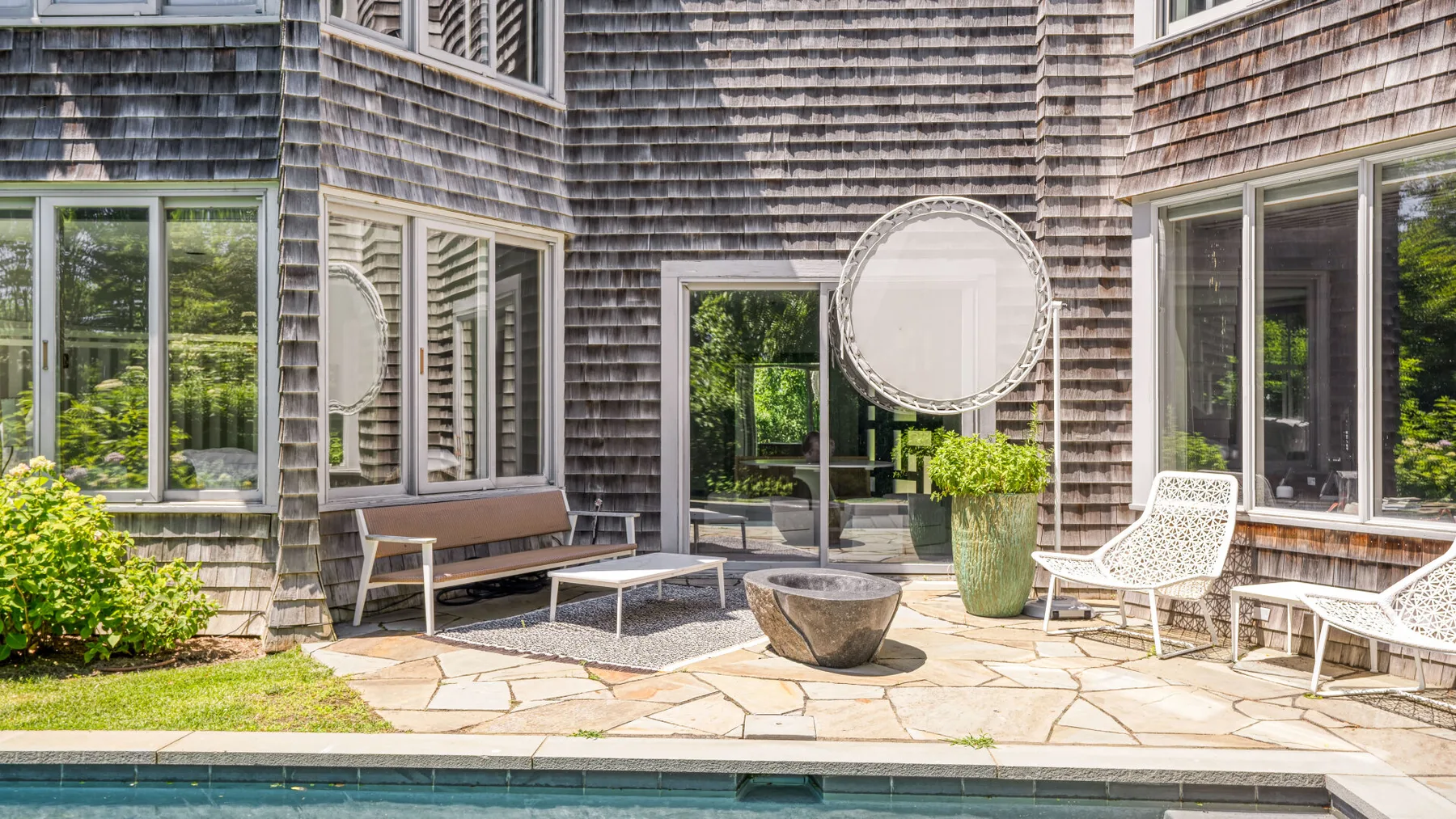 An outdoor patio with seating and a potted plant beside the house.