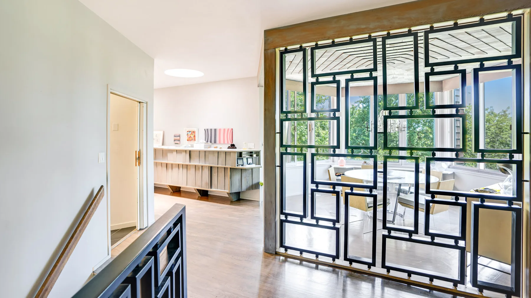 A bright interior hallway opens onto a sitting area behind a geometric divider.