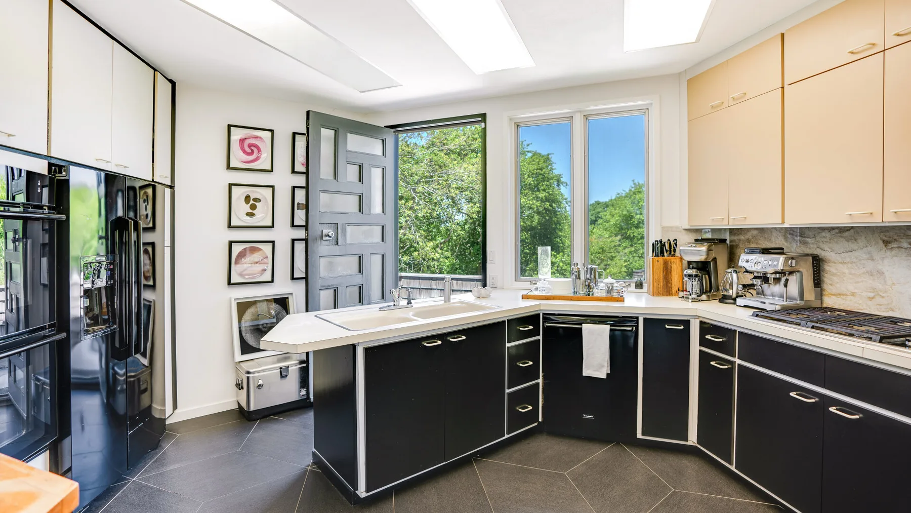A bright kitchen with dark lower cabinets, light upper cabinets, and an island.