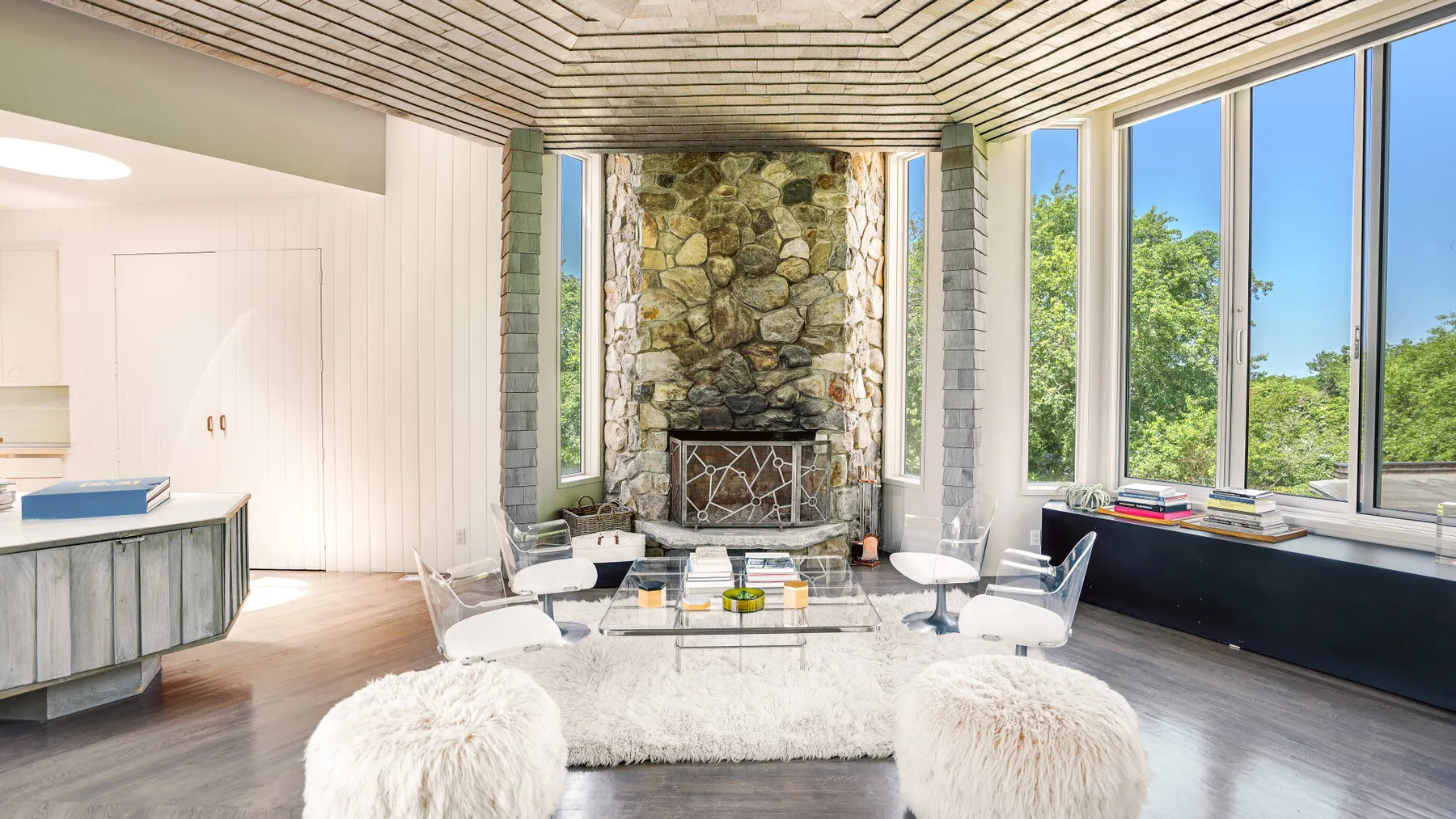 A bright living room with a stone fireplace and large windows.