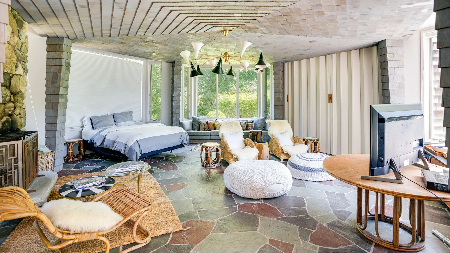 A bright living room with seating, a television, and large windows.