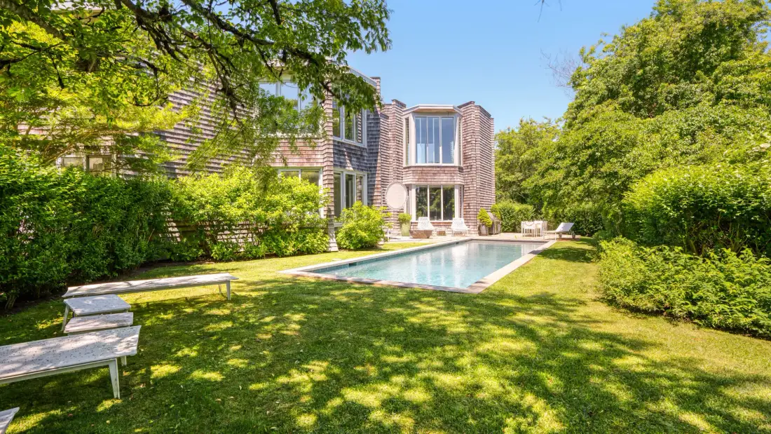 A house and swimming pool are set within a leafy garden.
