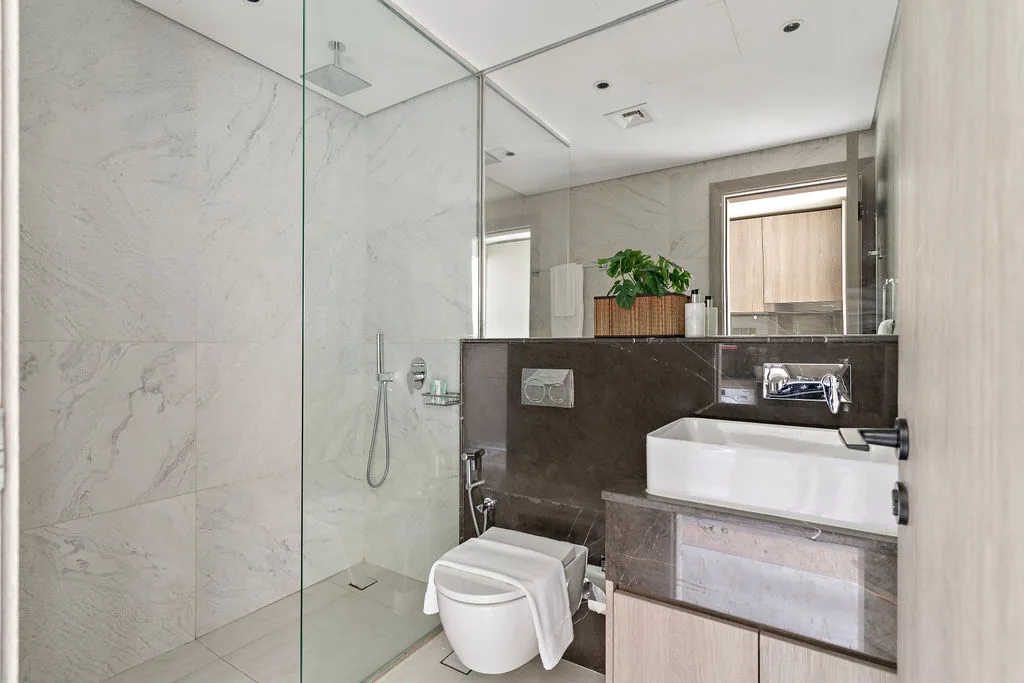 Un baño moderno con ducha de vidrio, inodoro y tocador.