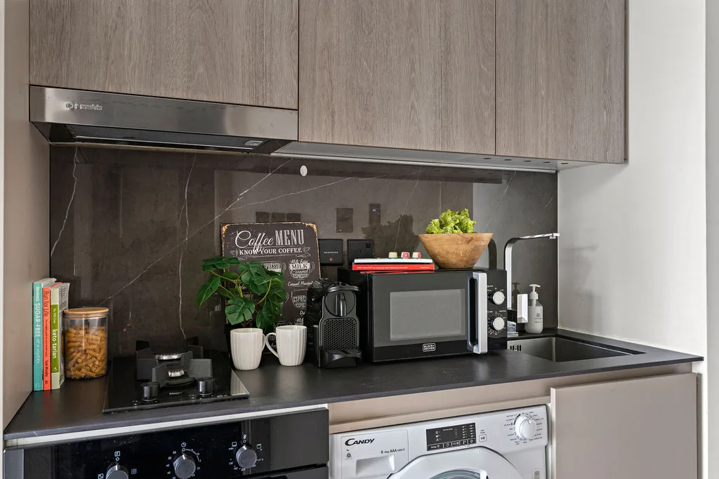 Una encimera de cocina moderna con microondas, artículos de café y armarios superiores.
