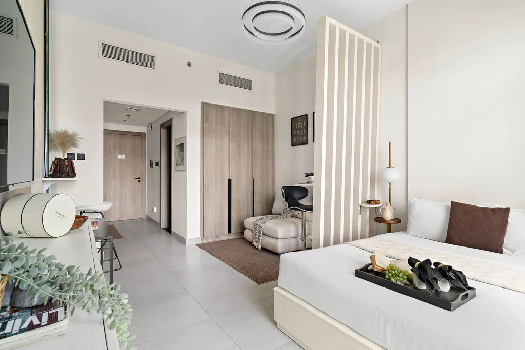 Un dormitorio luminoso con una cama, una zona de estar y un separador independiente.