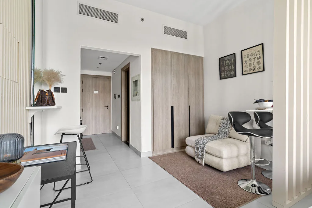 Un dormitorio luminoso con una cama baja junto a un armario y una pequeña zona de comedor.