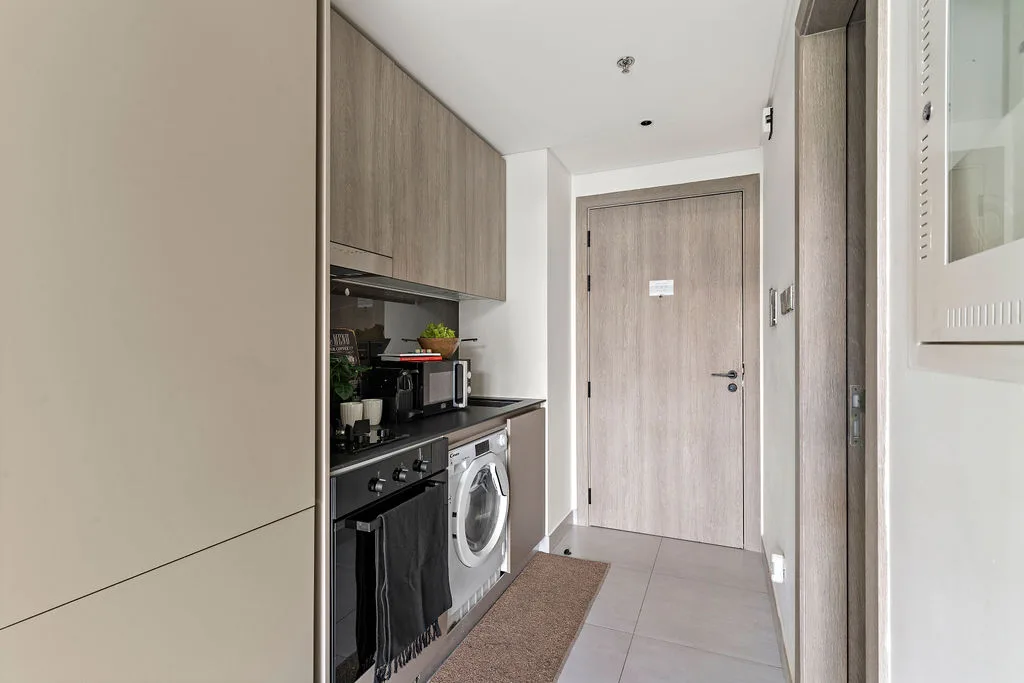 Una cocina estrecha da a un pasillo de baldosas con una puerta cerrada.