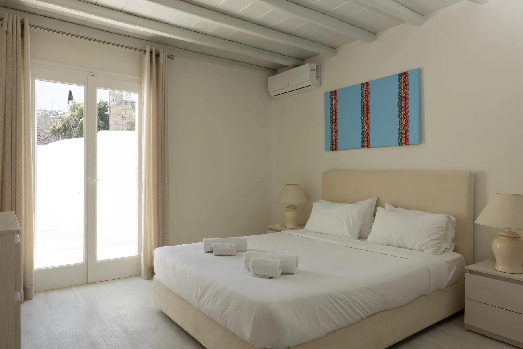 A bedroom with a neatly made bed and sliding glass doors.