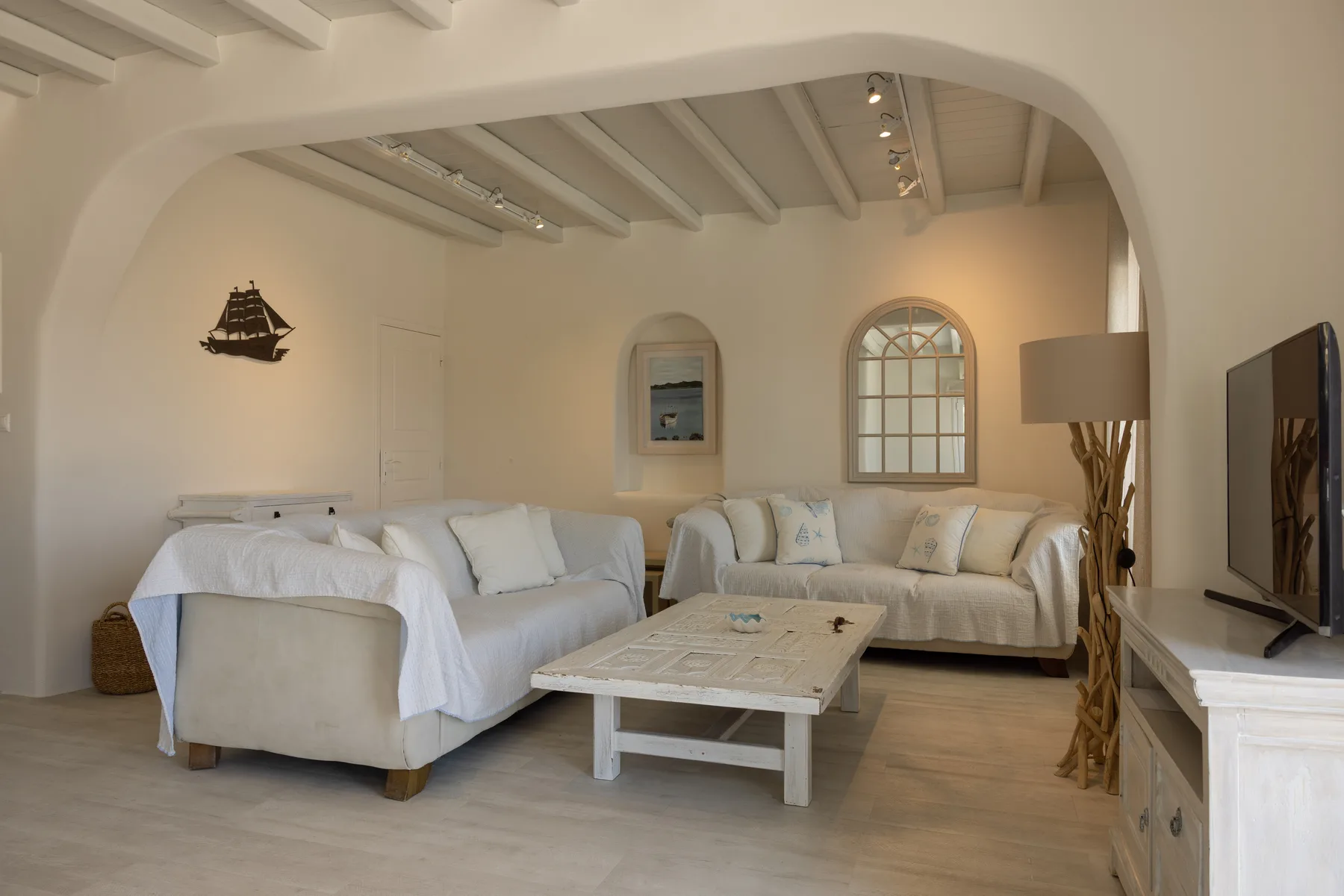 A bright living room with a seating area, coffee table, and television.