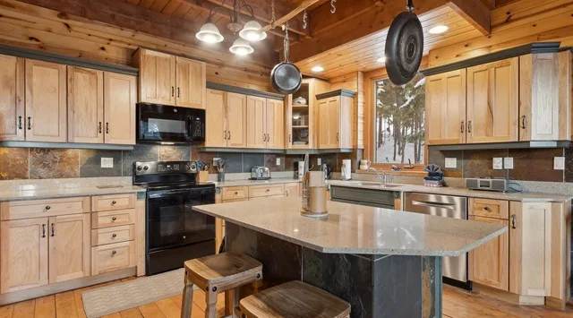 A spacious kitchen with wooden cabinetry, stainless steel appliances, and a large central island.