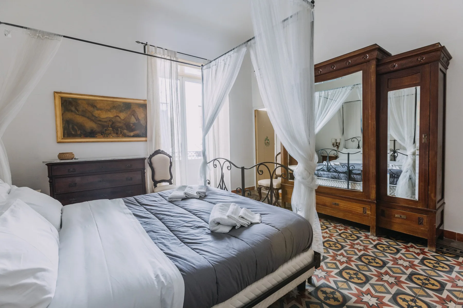 Un dormitorio con una cama, cortinas translúcidas y un armario grande de madera.