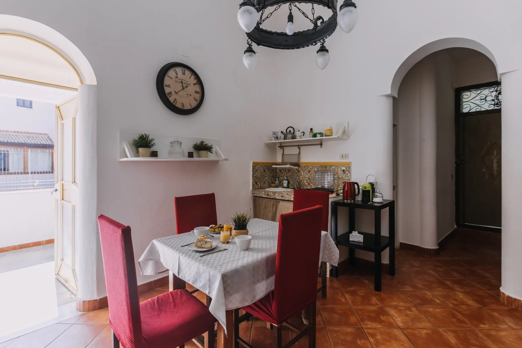 A dining area with a table and red seating beside a small kitchen.
